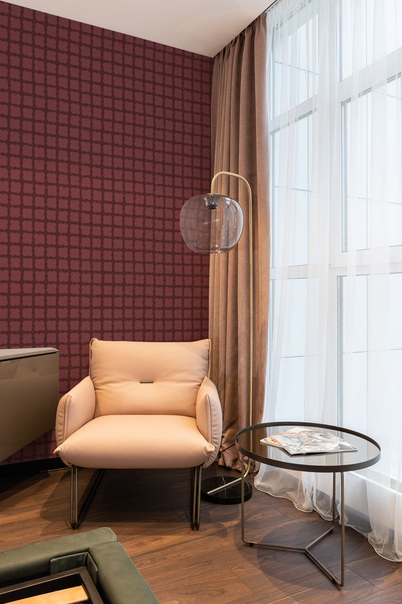 A cozy room corner with a chair and side table against a wall covered in a seamless flower print wallpaper in a deep red hue, complementing the traditional wallpaper theme.