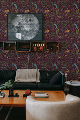 A room with burgundy wallpaper adorned with a pattern of animals and foliage, alongside furniture, creating a cozy ambiance with traditional wallpaper.