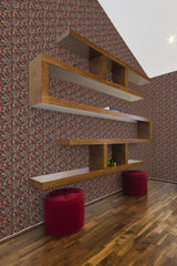 A room with a wall covered in burgundy garden-themed wallpaper with a repeated floral pattern in red and gold hues, accented by floating wooden shelves and matching burgundy poufs, giving the space a classic touch of traditional wallpaper.