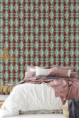 A room with a bed in front of a wall covered in Burgundy modern print wallpaper with geometric shapes in burgundy, beige, and green tones, reflecting a traditional wallpaper style.