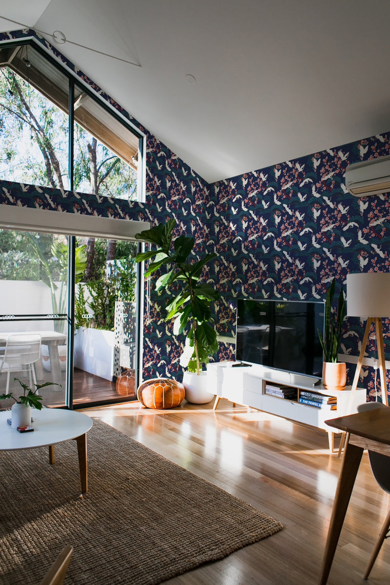 A room with walls covered in traditional wallpaper with a bold pattern of cranes amidst floral motifs on a dark blue background.