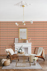 A room with a wall covered in Retro triangles wallpaper, consisting of geometric patterns with a combination of red, yellow, and green hues, complemented by simple furniture and traditional wallpaper.