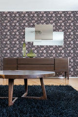 A room with washed-out floral wallpaper with muted purple and pink tones on the walls, complementing dark wooden furniture and a blue shaggy rug, embodying a traditional wallpaper.