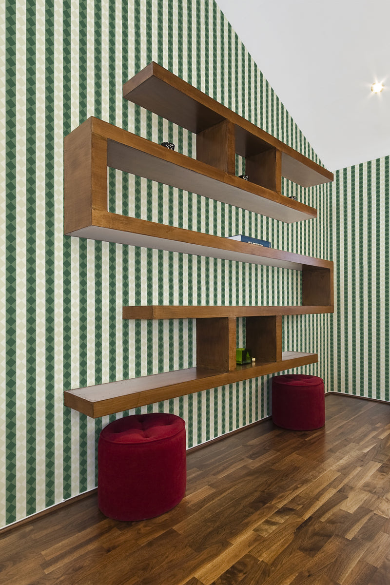 A room with green and white striped retro geometry wallpaper on one wall, accompanied by a wooden shelving unit and two red stools, reflecting a traditional wallpaper style.