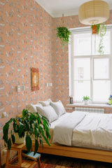 A bedroom with peach-colored wallpaper adorned with playful cat illustrations and complementary houseplants, described as Cute Kitties traditional wallpaper.