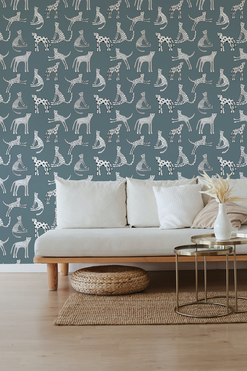 A room with a wall covered in wallpaper with illustrations of playful kittens in various poses, set against a muted background, complementing a minimalist sofa and a simple decor, traditional wallpaper.