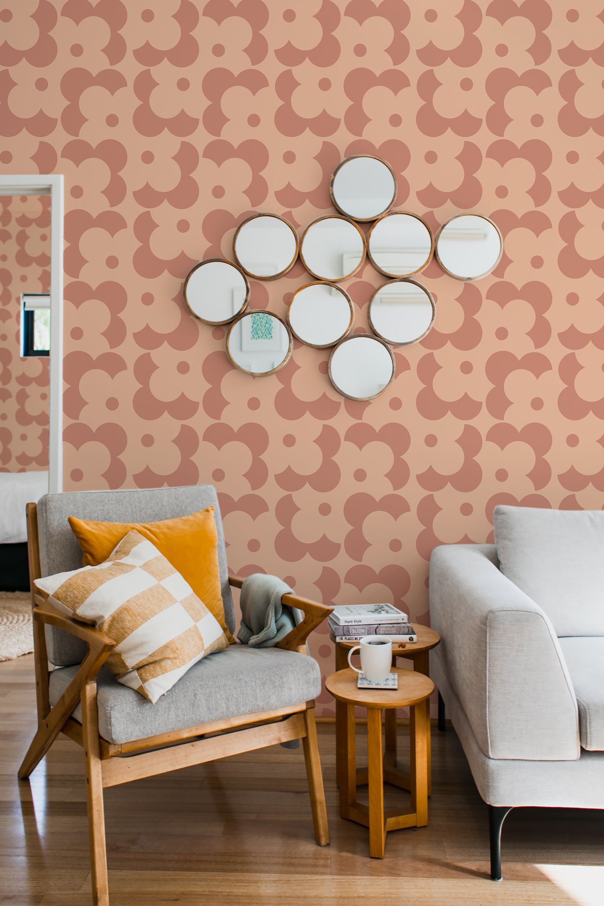 A room with peach-colored wallpaper with a simple retro circular pattern, accented by a cluster of round mirrors, complemented by a wooden chair and sofa, embodying traditional wallpaper.