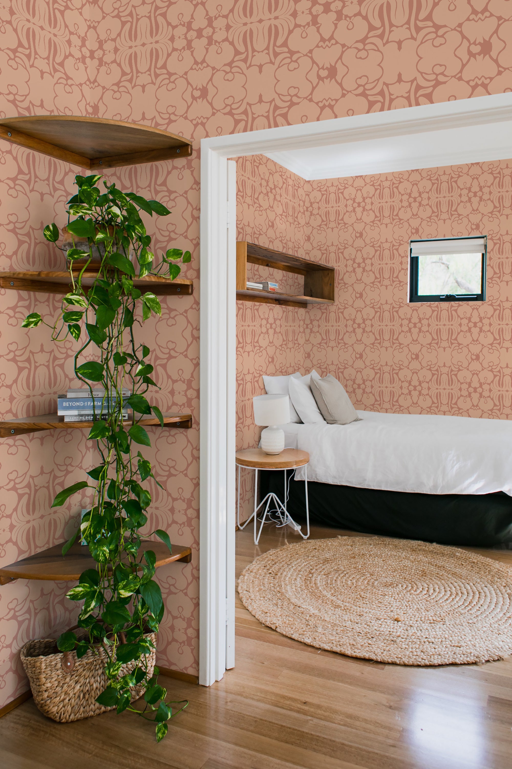 A room with peach-colored Victorian-style wallpaper with intricate patterns, alongside wooden shelves and a plant, embodying traditional wallpaper.