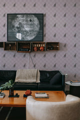 A living room with light pink and white checkered wallpaper adorned with illustrations of stylized dogs in fashionable outfits, complementing a cozy seating area, with a traditional wallpaper feel.