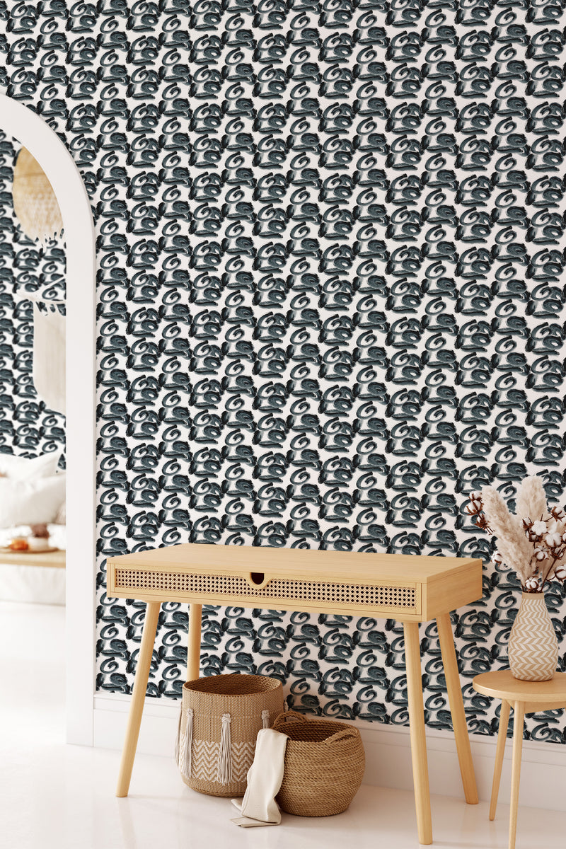 A room with a wall covered in monochrome brushstroke patterned wallpaper in a repeating black and white design, combined with a wooden console table and woven accessories, giving a contemporary twist on traditional wallpaper.