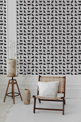 A room with white and black patterned 'Aesthetic cat' wallpaper, showing repeating silhouettes of cats in various poses on the walls, complemented by a wooden chair and plants, traditional wallpaper.