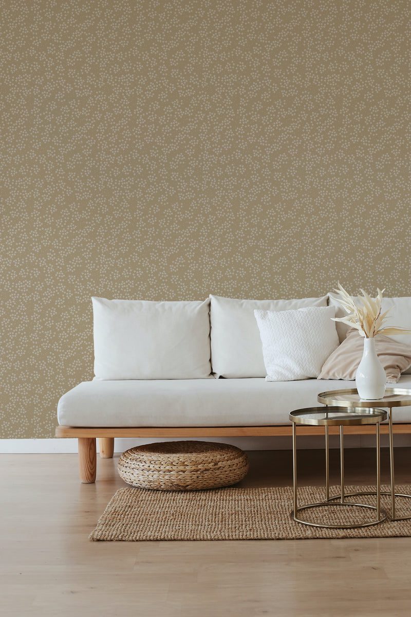 A room with a wall covered in brown floral wallpaper, complemented by a minimalist sofa, a woven ottoman, and a metal coffee table, evoking a traditional wallpaper aesthetic.