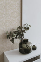 Self-adhesive wallpaper with elegant, neutral paisley pattern in a nursery room, accompanied by a decorative green vase with leaves on a white shelf.