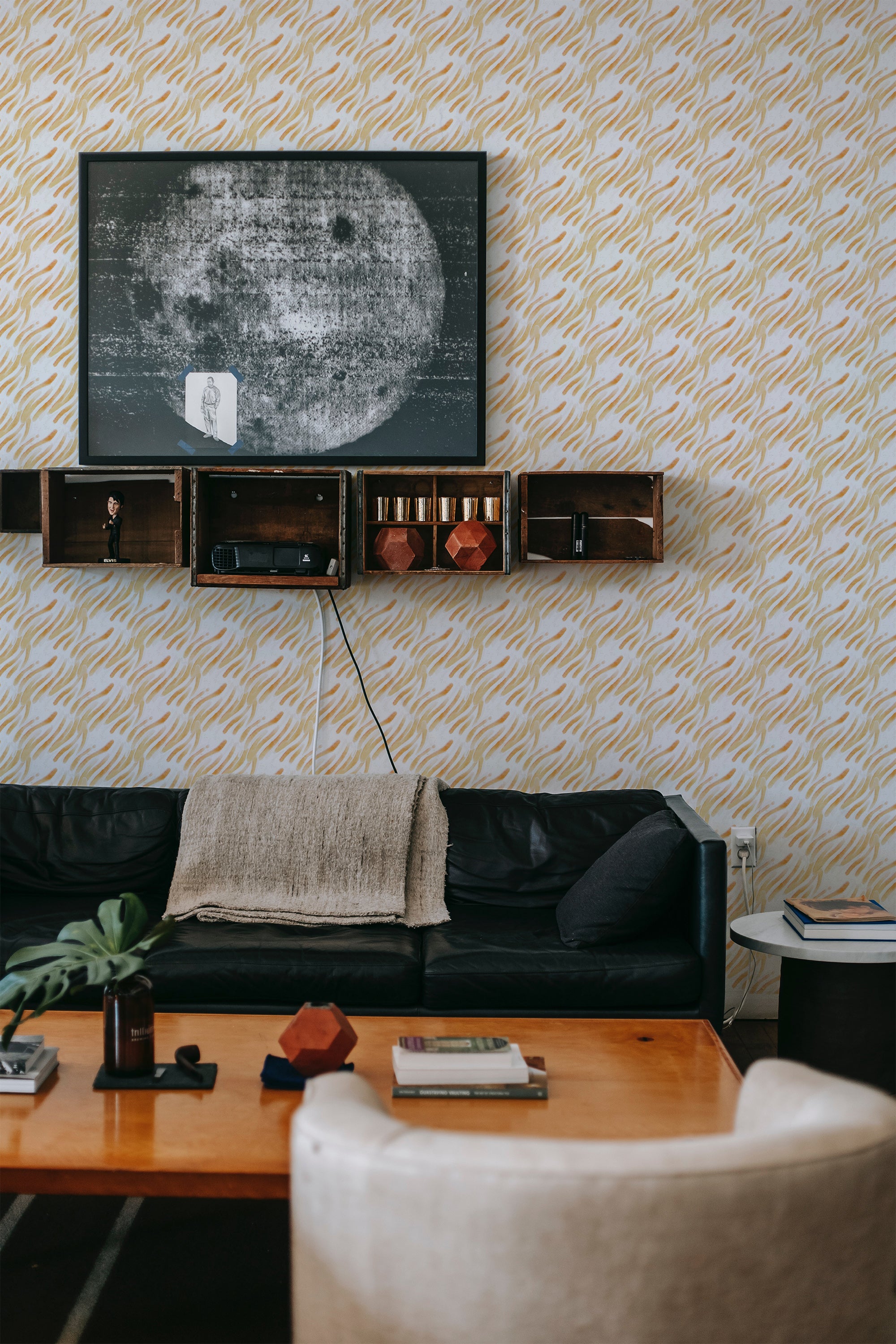 A room with yellow brush stroke patterned wallpaper, complemented by mid-century modern furnishings and traditional wallpaper.
