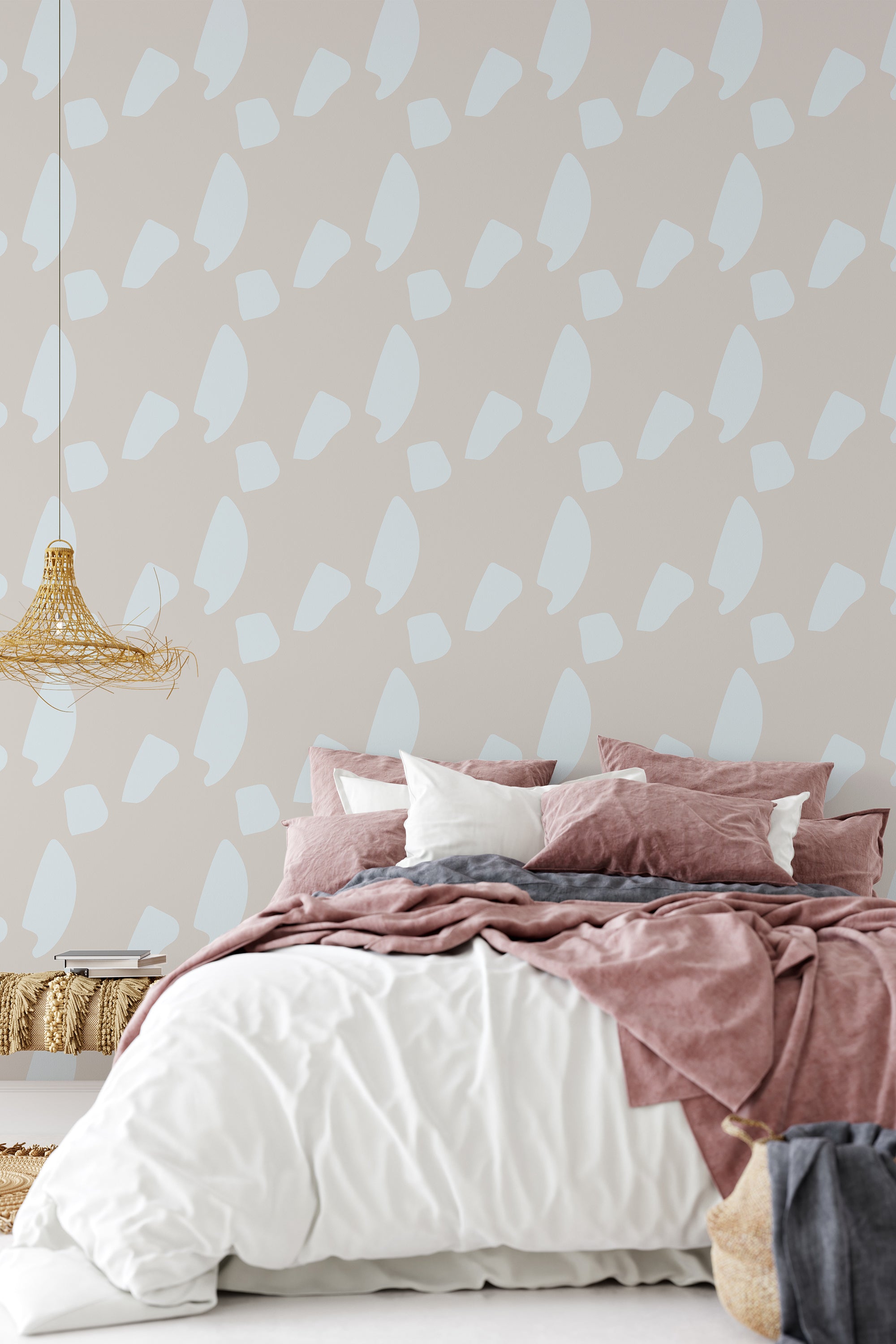 A bedroom with a wall covered in neutral-toned wallpaper with a geometric pattern of overlapping pale blue and white shapes on a taupe background, complementing a bed with pink and white bedding, traditional wallpaper.