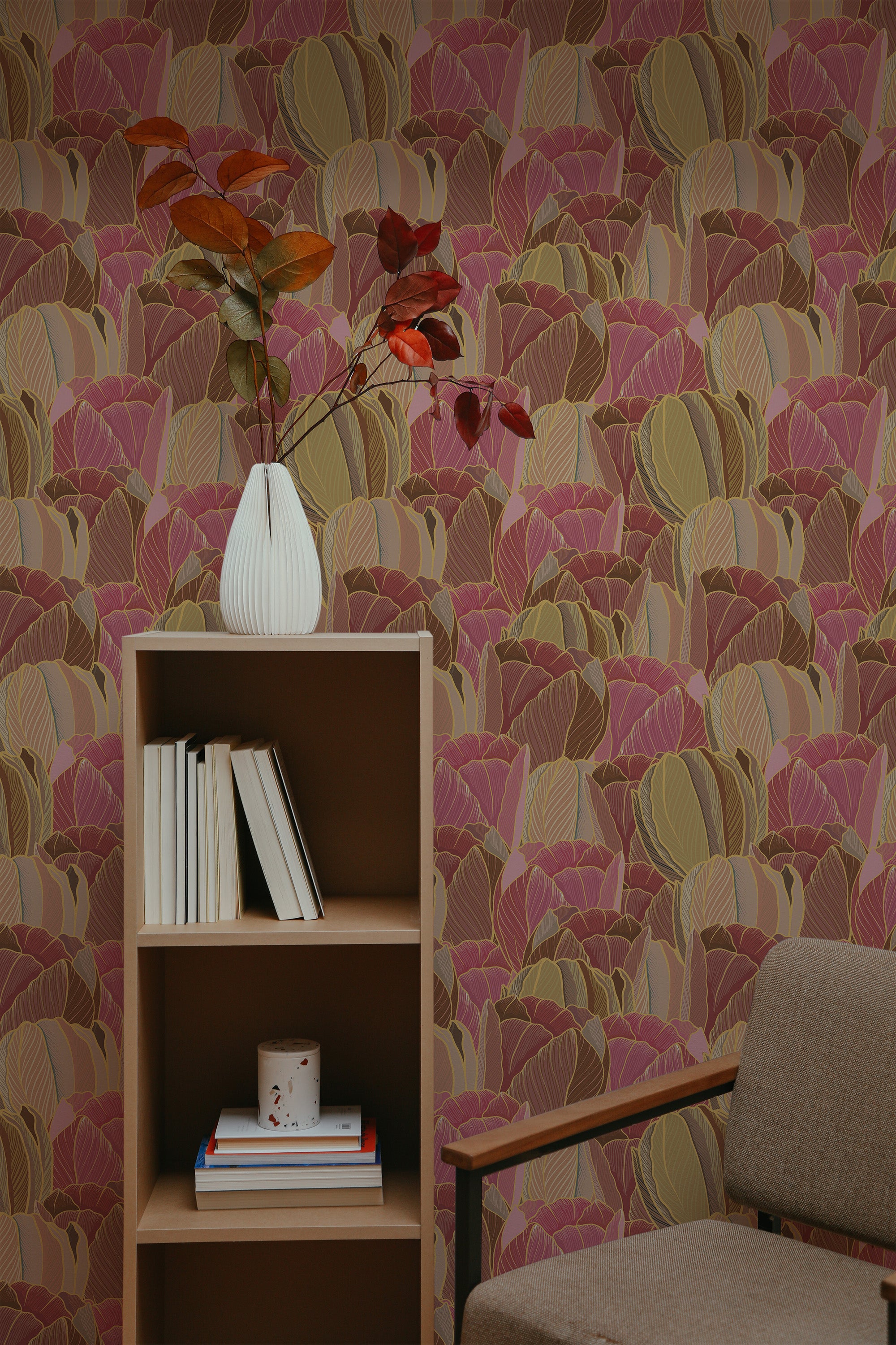 Self-adhesive wallpaper with a pattern of pink and ocher leaves design on a wall, accompanied by a wooden bookshelf, a vase, and a grey chair.