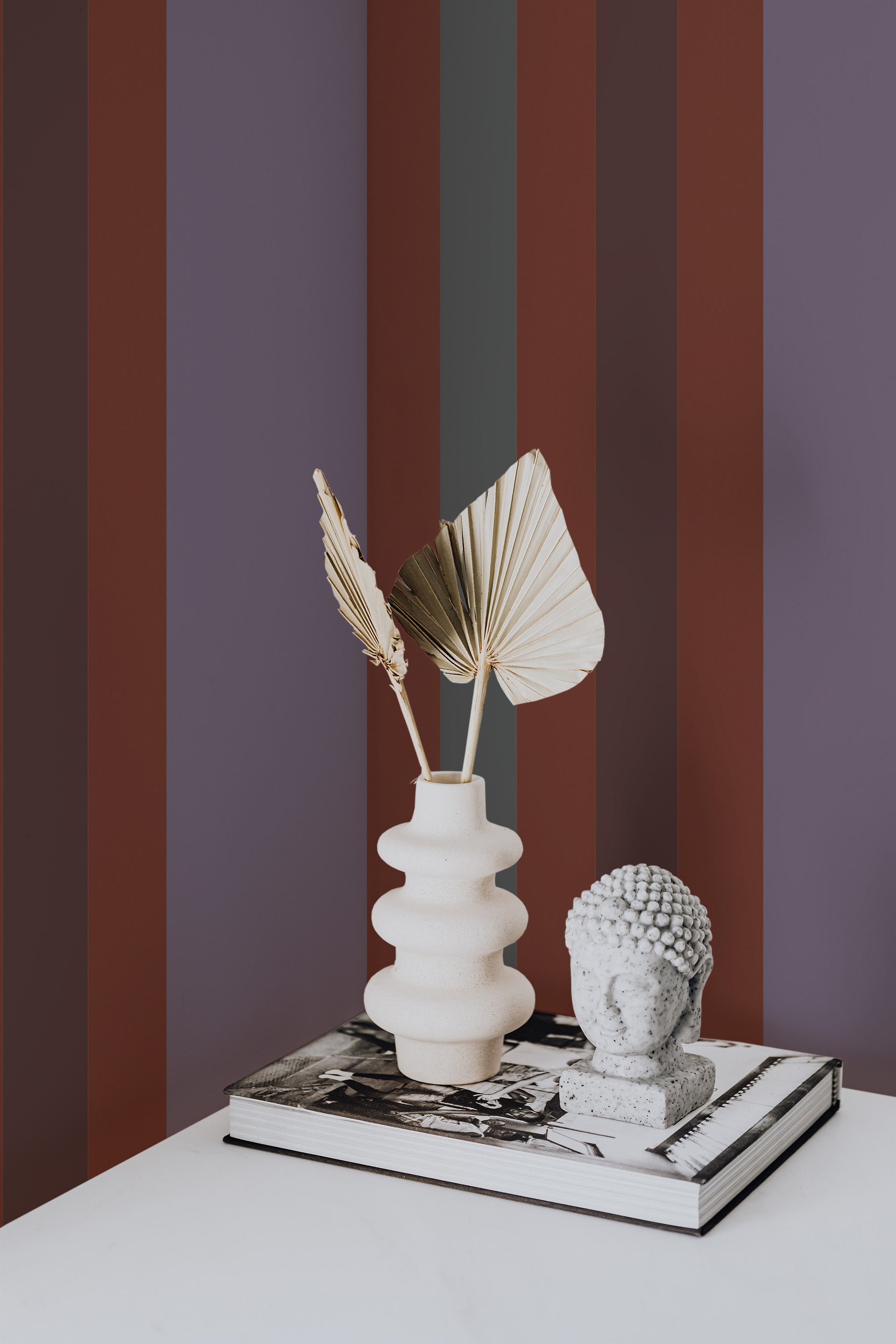 Self-adhesive Aesthetic Stripes wallpaper with vertical maroon and beige bands on a room wall, complemented by decorative items on a table.