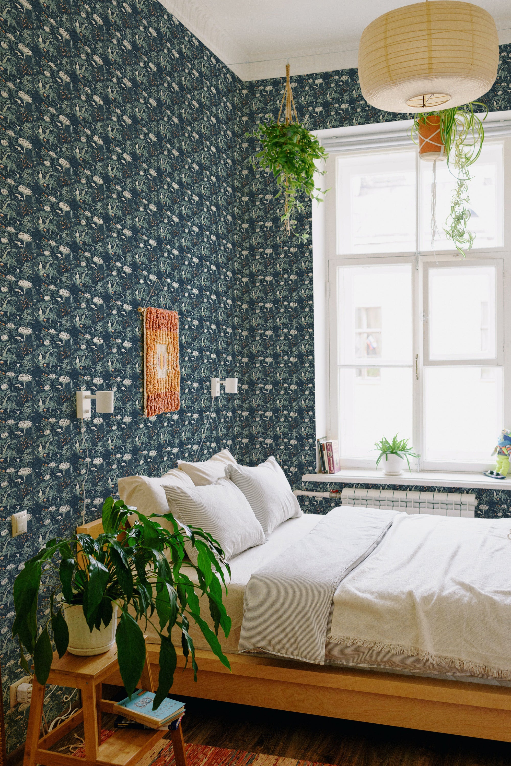 A cozy bedroom with a bed against a wall covered in Beautiful Midnight Meadow wallpaper, a dark backdrop with intricate light floral patterns, adding a timeless elegance to the space, traditional wallpaper.