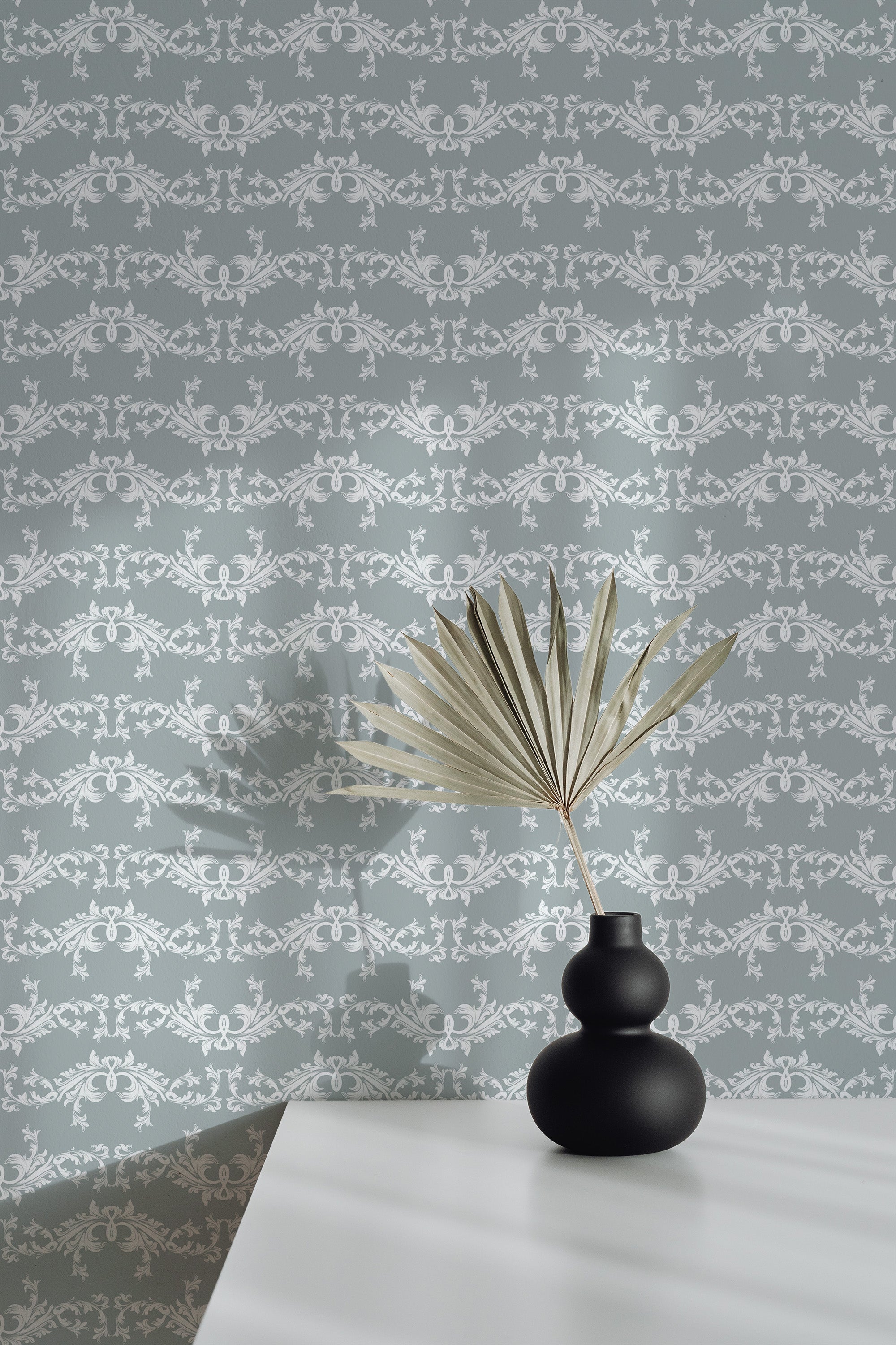 Self-adhesive Elegant damask wallpaper with intricate white and gray patterns on a room wall, complemented by a decorative vase and plant on a table.