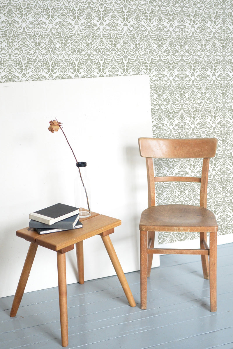 Self-adhesive Floral Art Deco wallpaper with intricate patterns in a room with a wooden chair and side table, books, and a lamp.