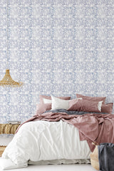 A bedroom with a wall covered in Elegant Blue and White traditional wallpaper with a delicate floral pattern.