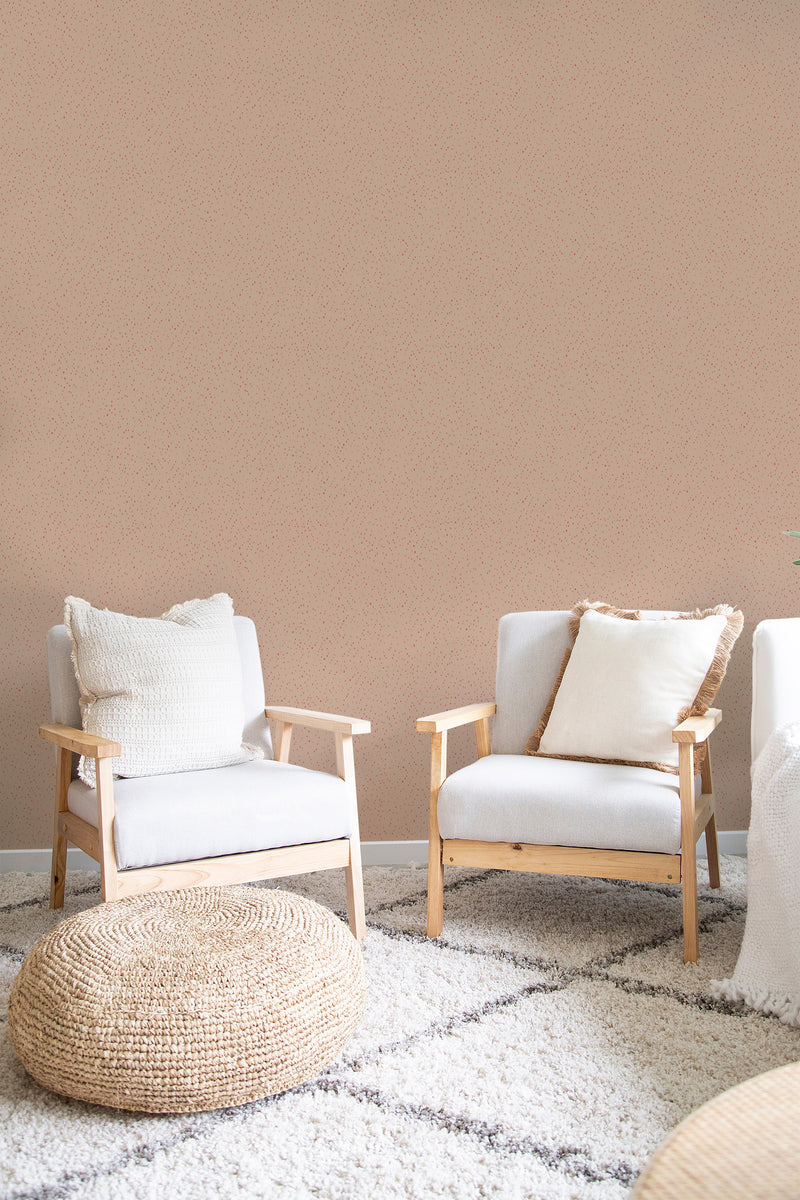 A room with tan walls adorned with red spots, complemented by two white chairs with wooden frames, a round woven ottoman, and a white fluffy rug, evoking a warm traditional wallpaper style.