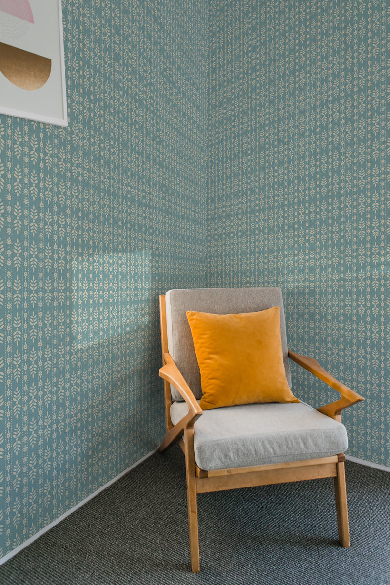 A room with pale blue wallpaper adorned with a white classic leaf pattern. A wooden chair with a grey cushion and bright yellow pillow sits in front, complementing the traditional wallpaper.