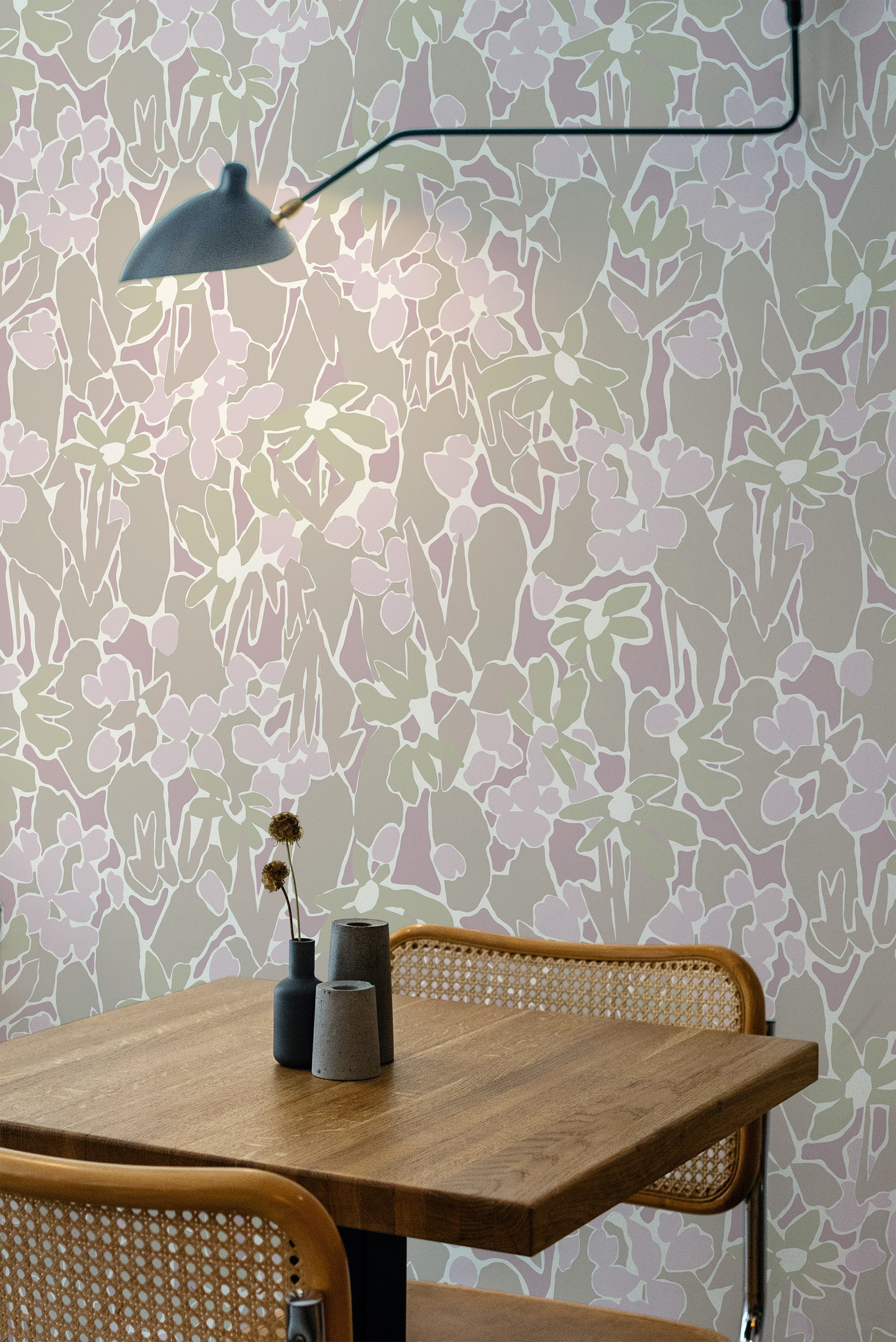 Self-adhesive wallpaper with an abstract neutral flower pattern in soft pastel tones on a room wall, accompanied by a wooden table and chair.