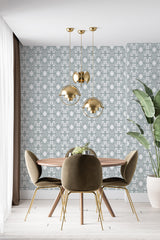 A room with Abstract Rainstorm wallpaper design on one wall, incorporating stylized raindrop patterns in shades of grey, behind a dining area with a wooden table, olive green chairs, and golden pendant lights, in a traditional wallpaper setting.