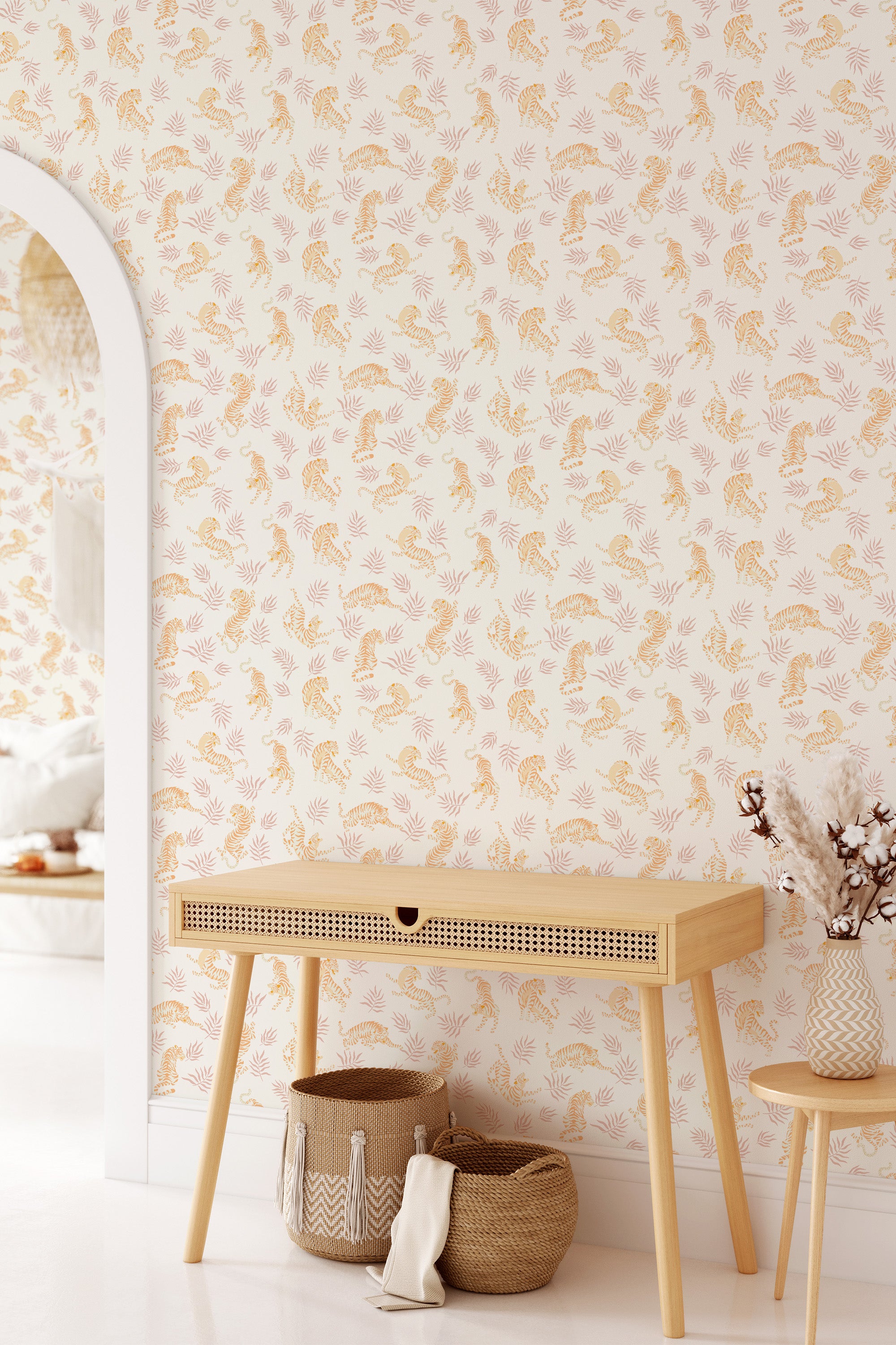 A room with a wall covered in 'Neutral Tigers' wallpaper with a subtle pattern of orange tigers and foliage on a cream background, above a wooden console table, embodying traditional wallpaper.