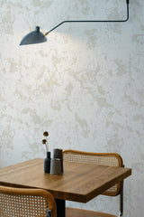 Self-adhesive limewash pattern wallpaper with a distressed look, in neutral tones on a room's wall above a wooden table with a vase and dried flowers.