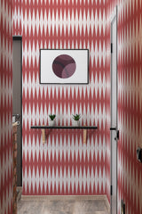 A room with Bold Slim Harlequin patterned wallpaper in deep maroon and white, creating a dynamic diamond motif, complemented by a framed abstract artwork and two potted plants on a floating shelf, traditional wallpaper.