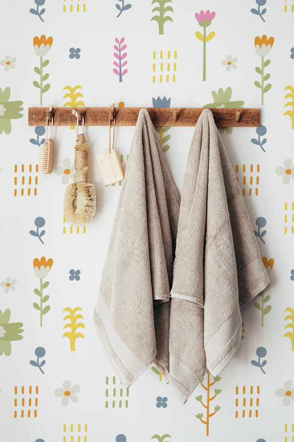 Self-adhesive wallpaper with a Cute Birdie design, including stylized birds, flowers, and leaves in a playful and colorful pattern, with towels hanging in front.