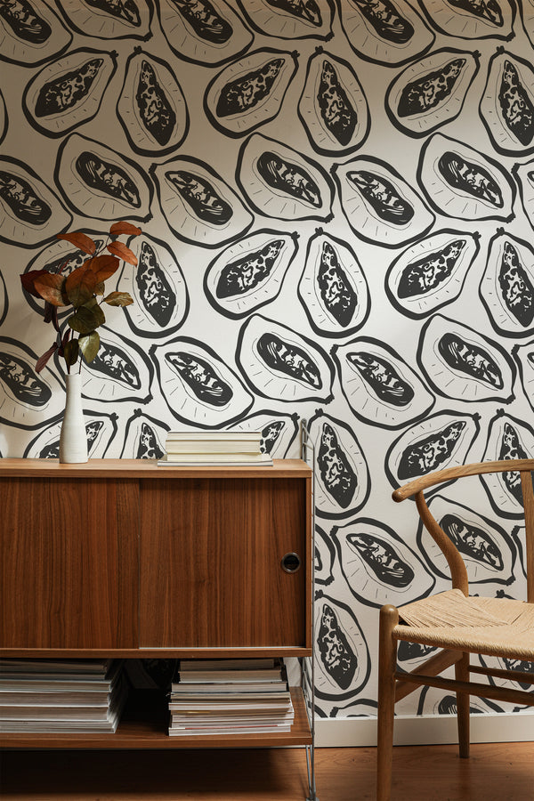 Self-adhesive wallpaper with a repeated papaya fruit pattern in black and white, complementing a stylish interior with a wooden sideboard and chair.