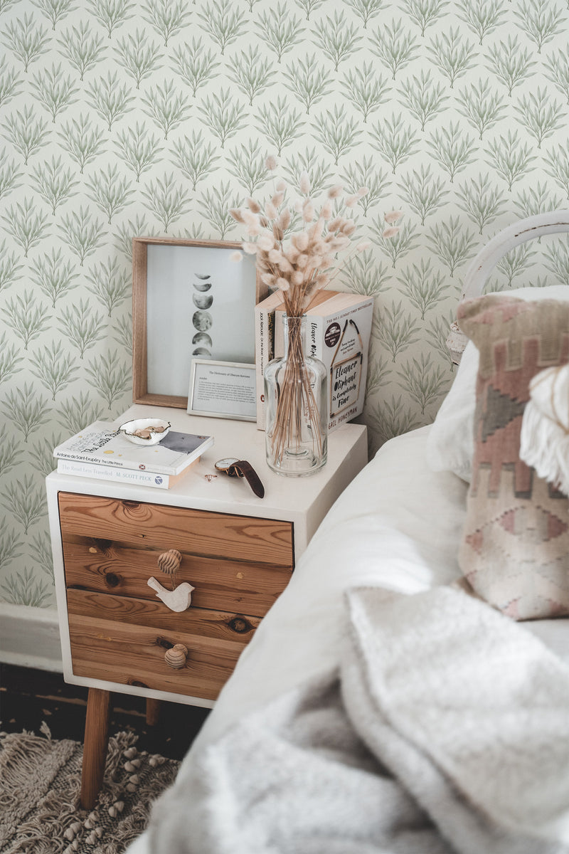 Self-adhesive wallpaper with a delicate olive branch pattern in a neutral color scheme adorns the wall of a cozy bedroom, complemented by a bedside table and decor.