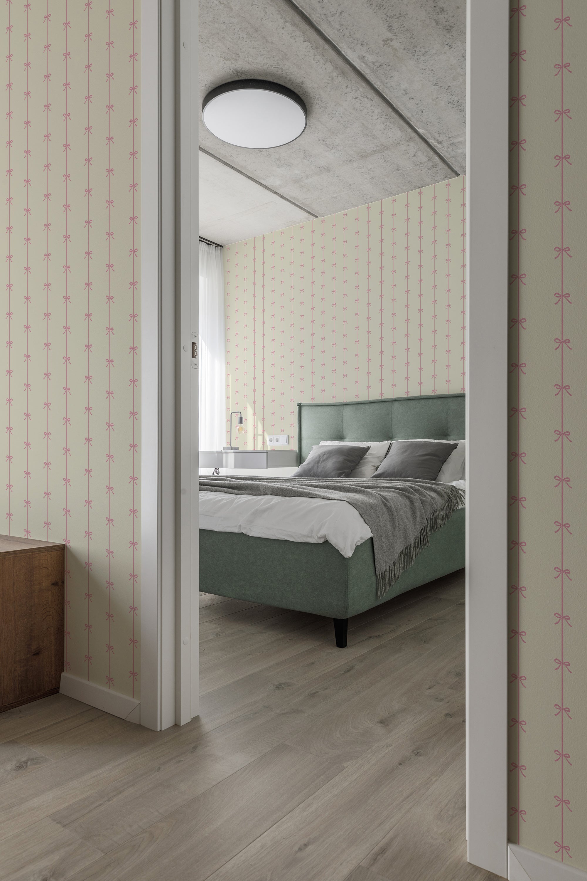 A bedroom with pale pink wallpaper adorned with vintage bow lines in a repeated pattern, complementing a green upholstered bed, traditional wallpaper.