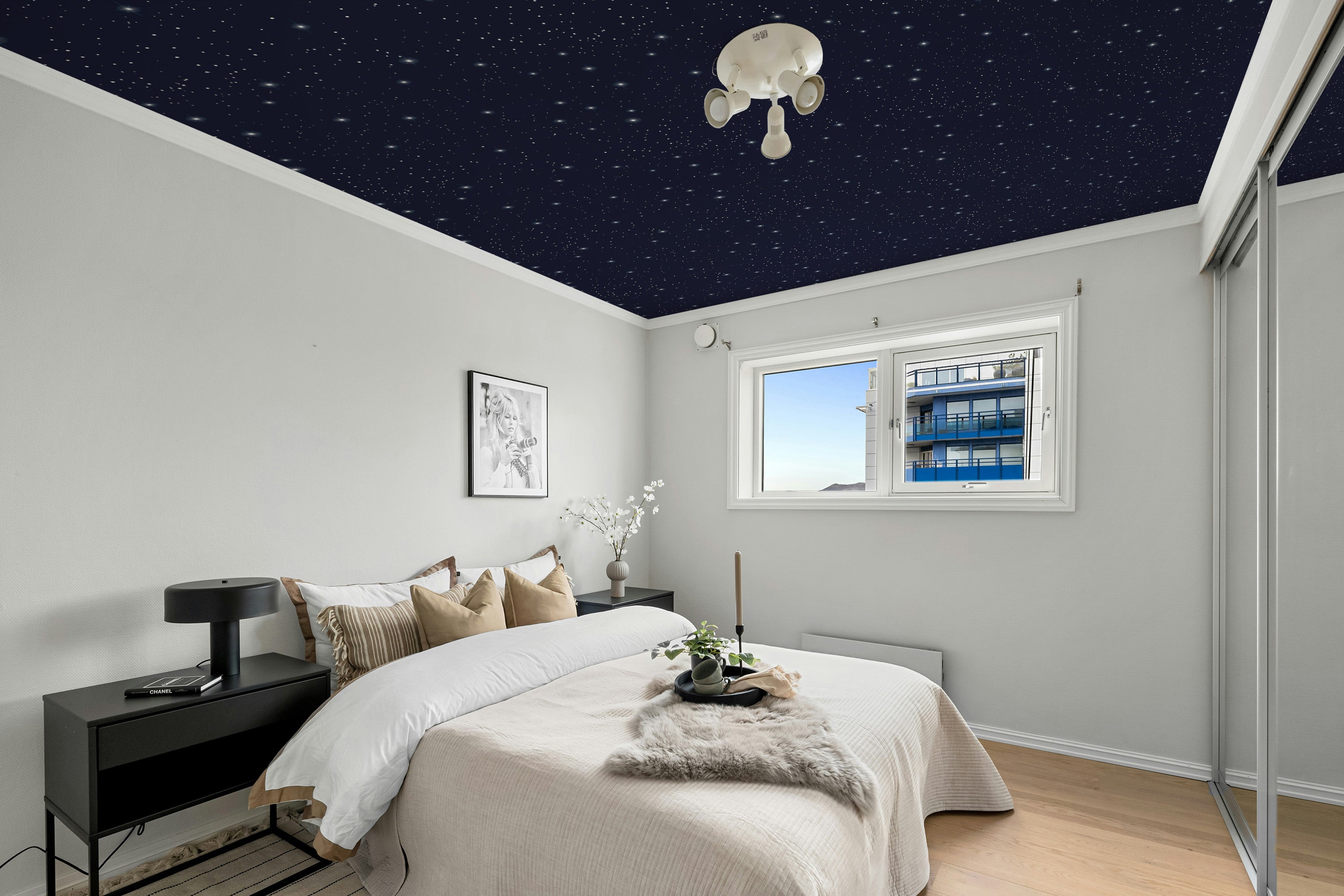 Modern bedroom with starry ceiling effect, bed, nightstands, and decor.