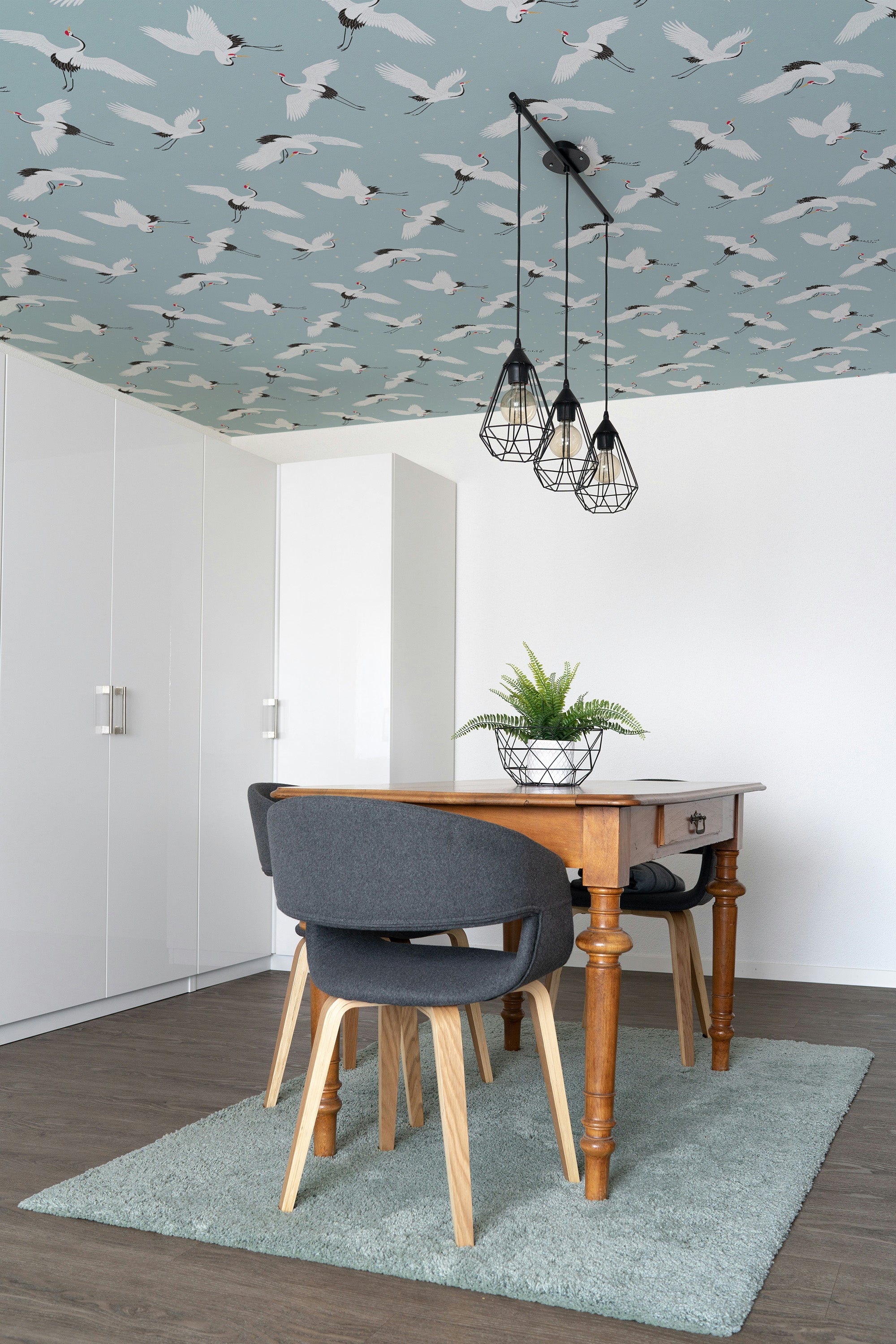 Dining room with wooden table, gray chairs, and ceiling with bird pattern.