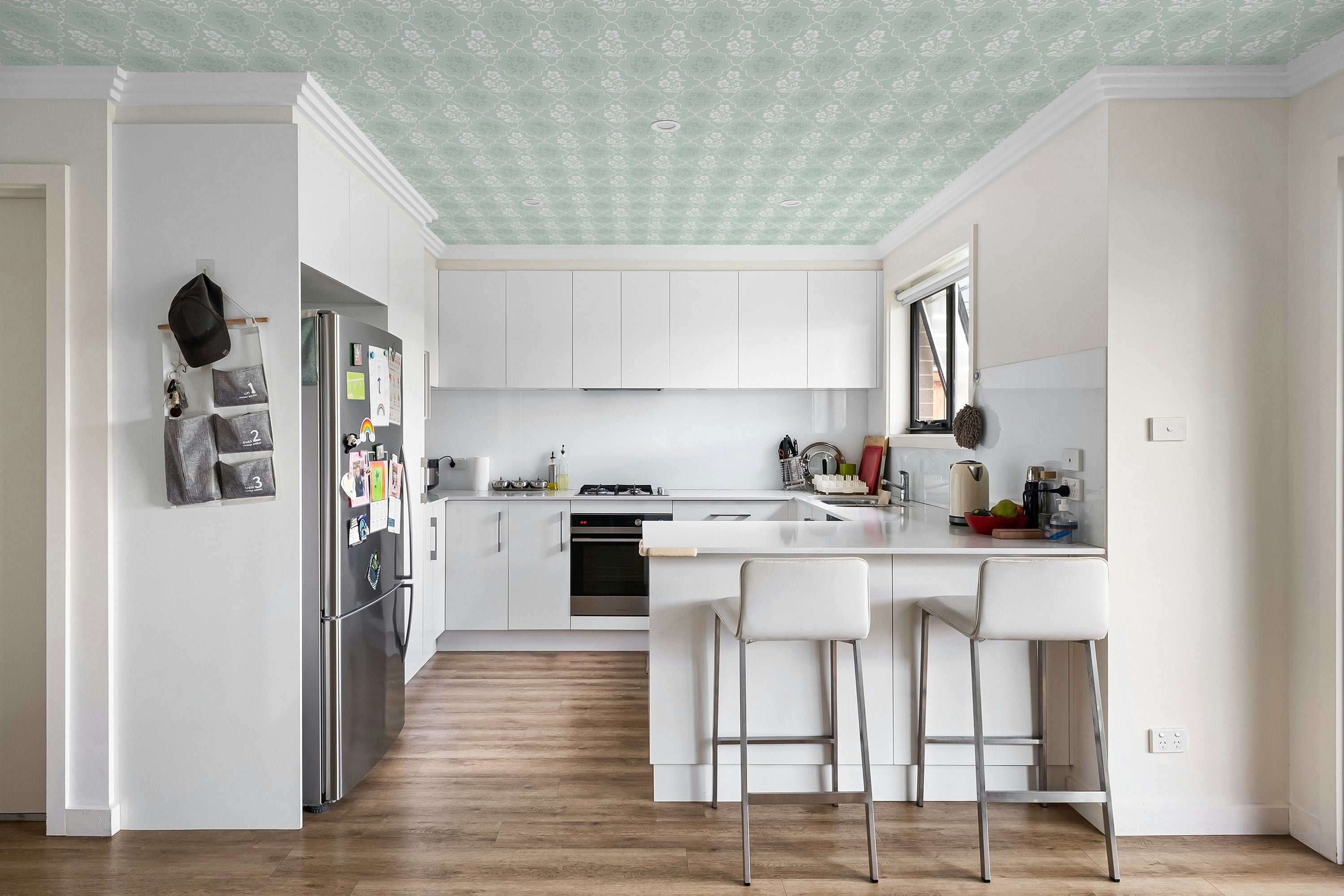 Modern kitchen with white cabinets, stainless steel appliances, and a green ceiling.