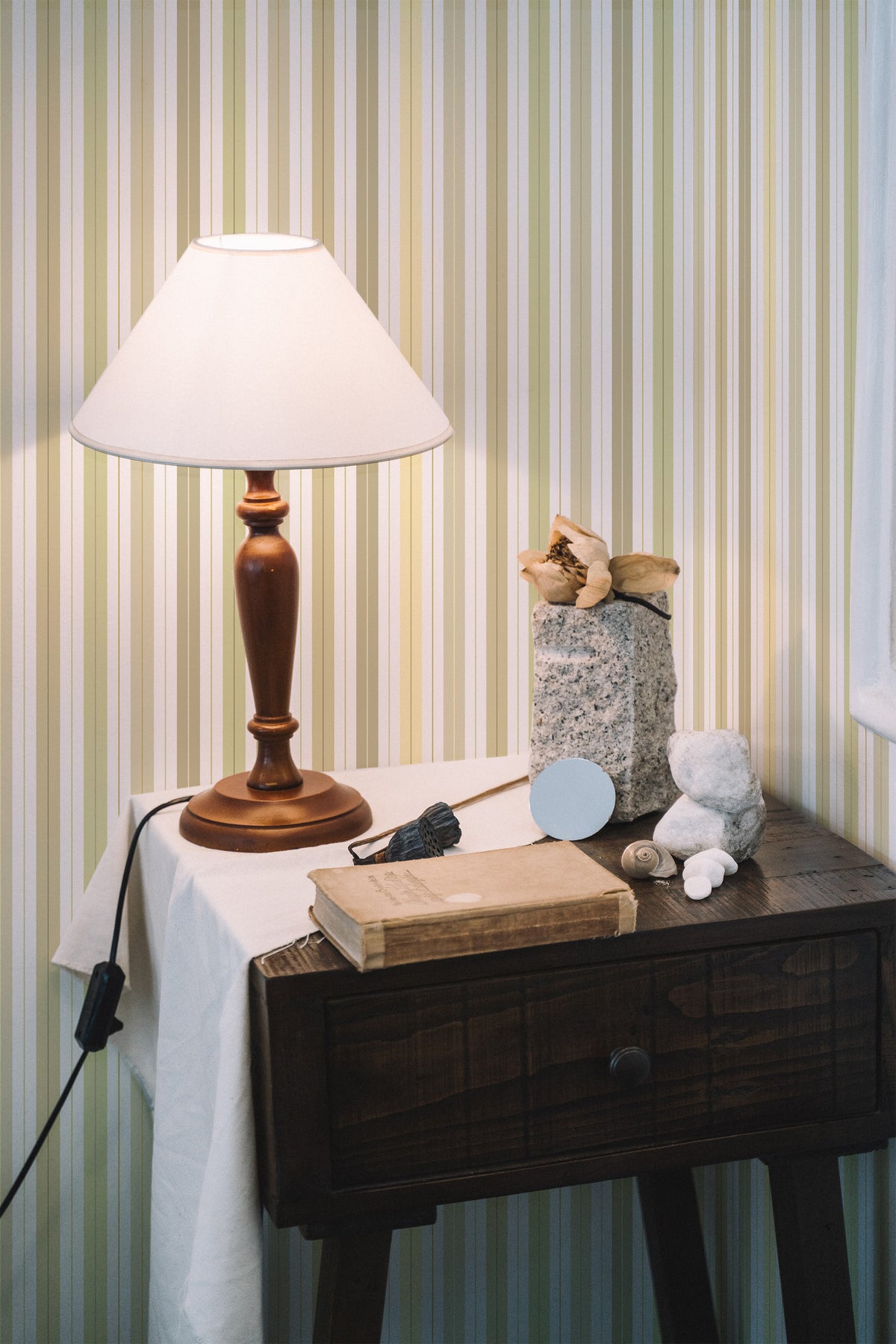 Soft Vertical Stripes grasscloth wallpaper on a styled interior wall with pale green and cream vertical stripes.