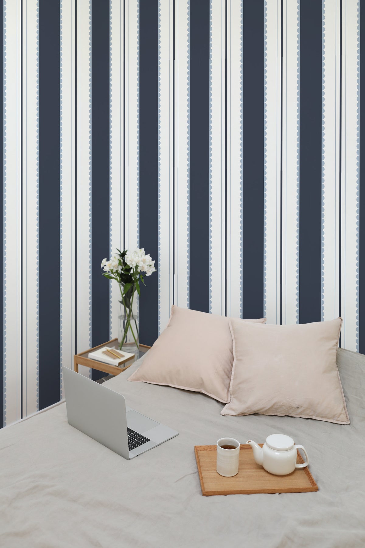 Scalloped Stripe Columns self-adhesive wallpaper in a bedroom, shown as a full-wall striped feature behind the bed.