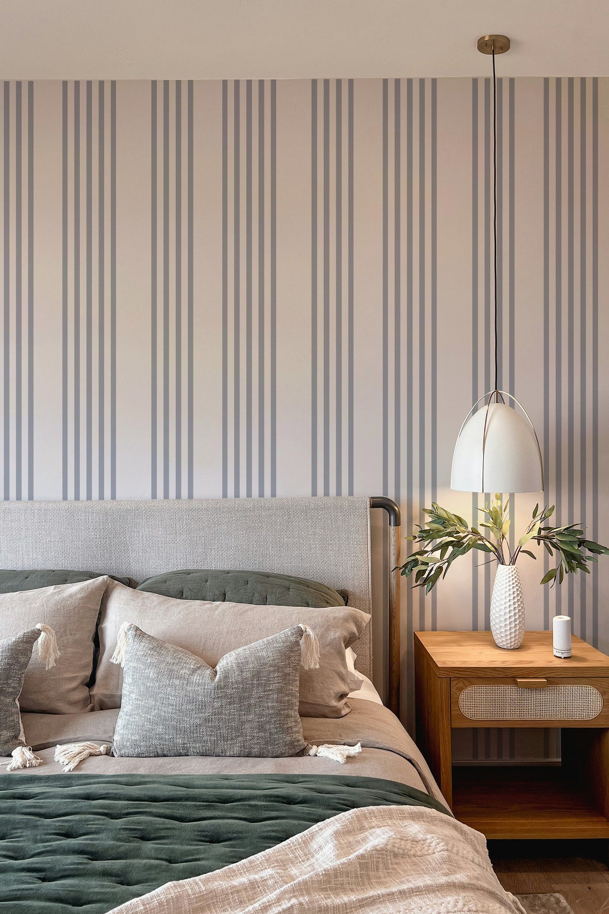 Classic Blue Pinstripes peel and stick wallpaper in a bedroom, blush ground with slim blue-gray vertical stripes.