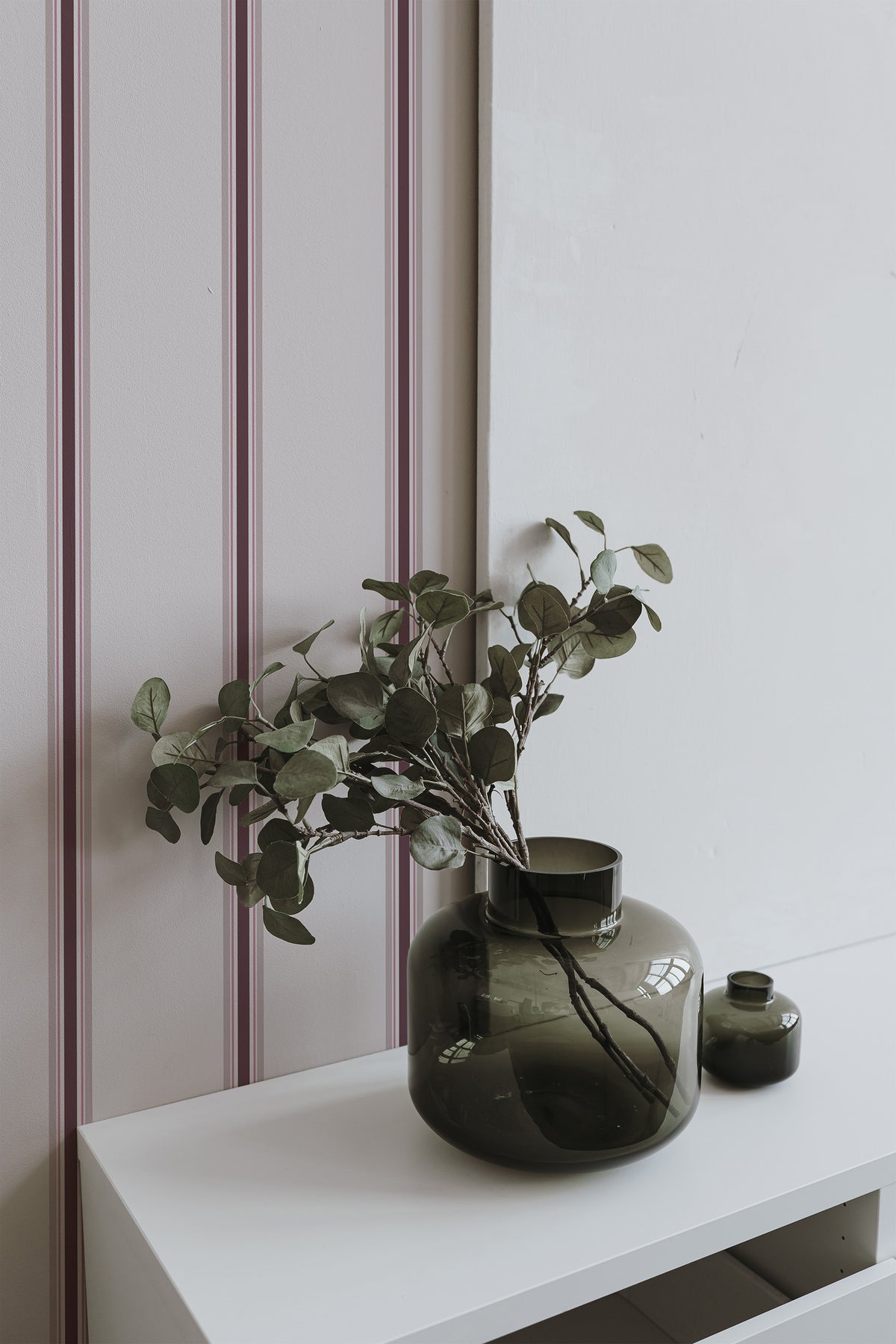 Crisp Stripe Columns peel and stick wallpaper on an interior wall with burgundy and blush vertical stripes.