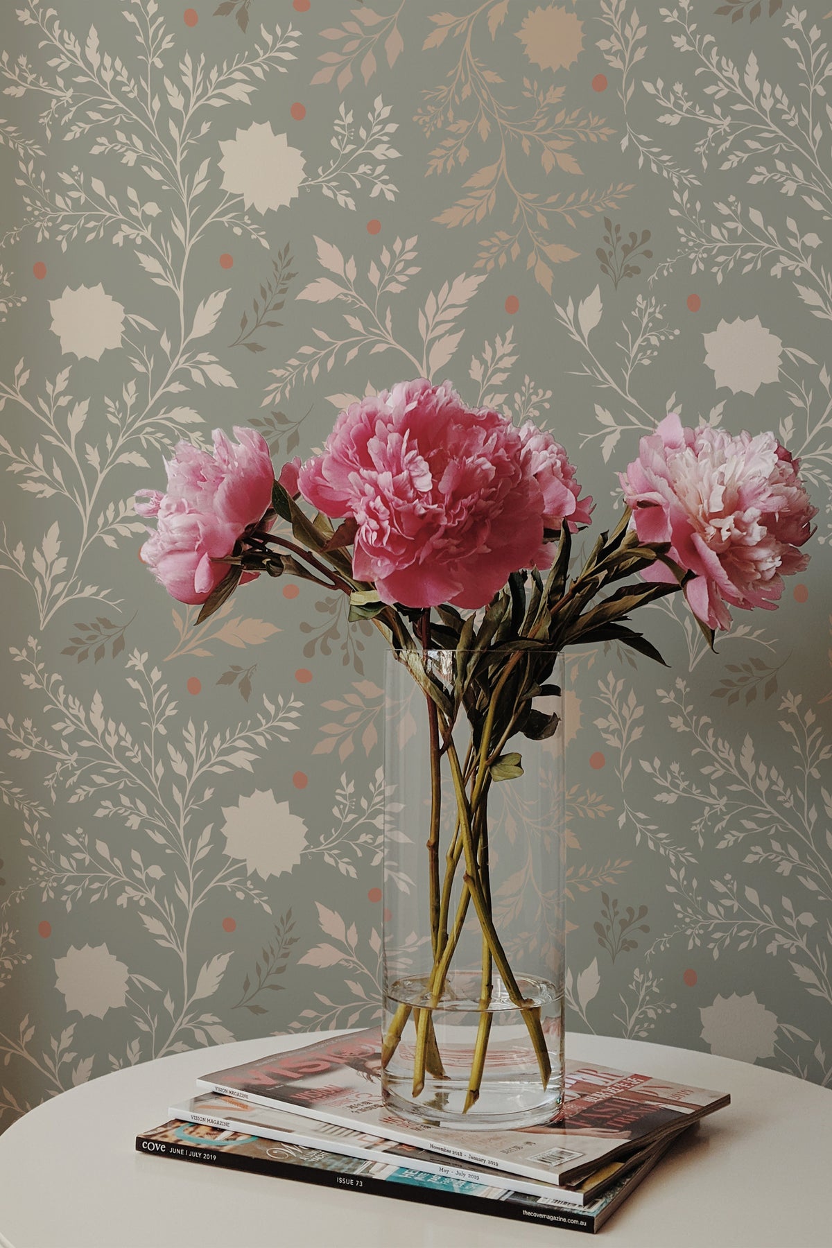 Delicate Floral Sprigs grasscloth wallpaper on an interior wall, with leafy sprigs on a muted green background.