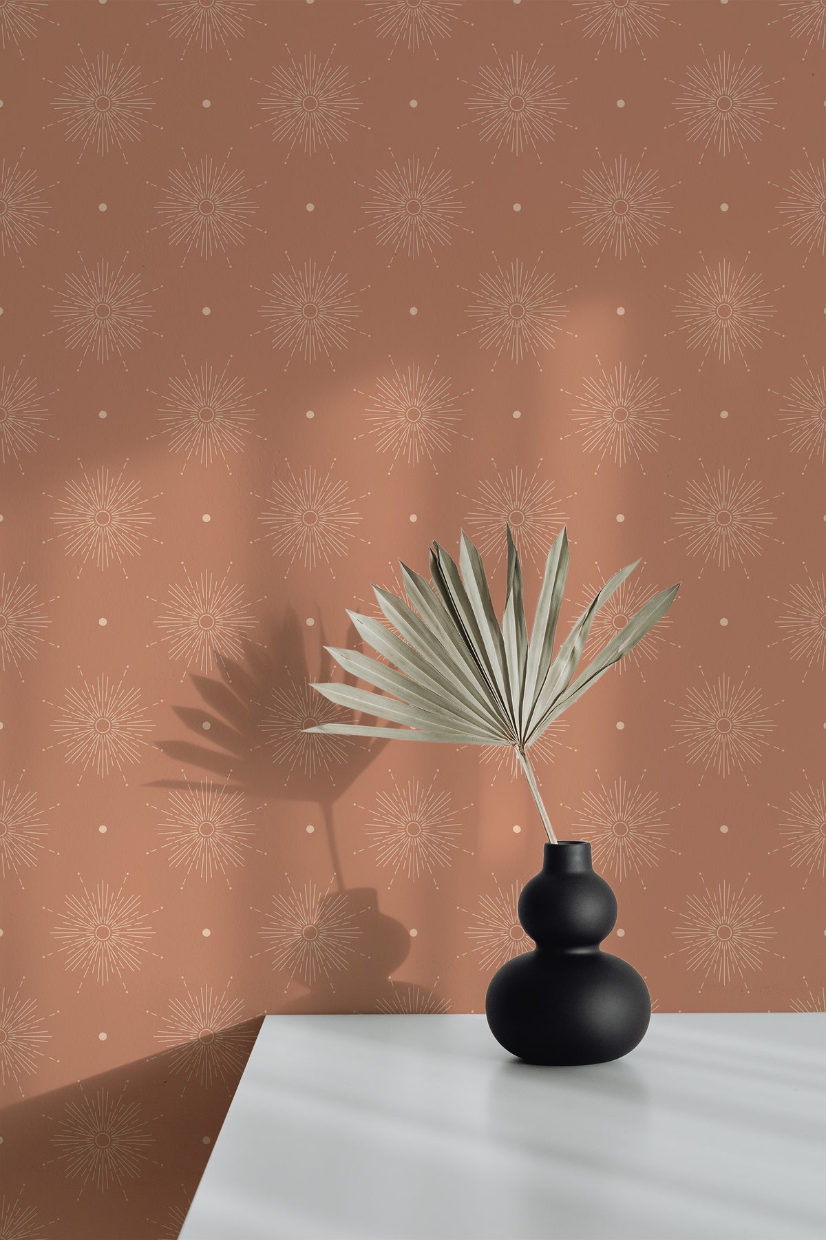 Radiant Sunbursts peel and stick wallpaper on an interior wall with off-white sunburst motifs on terracotta.