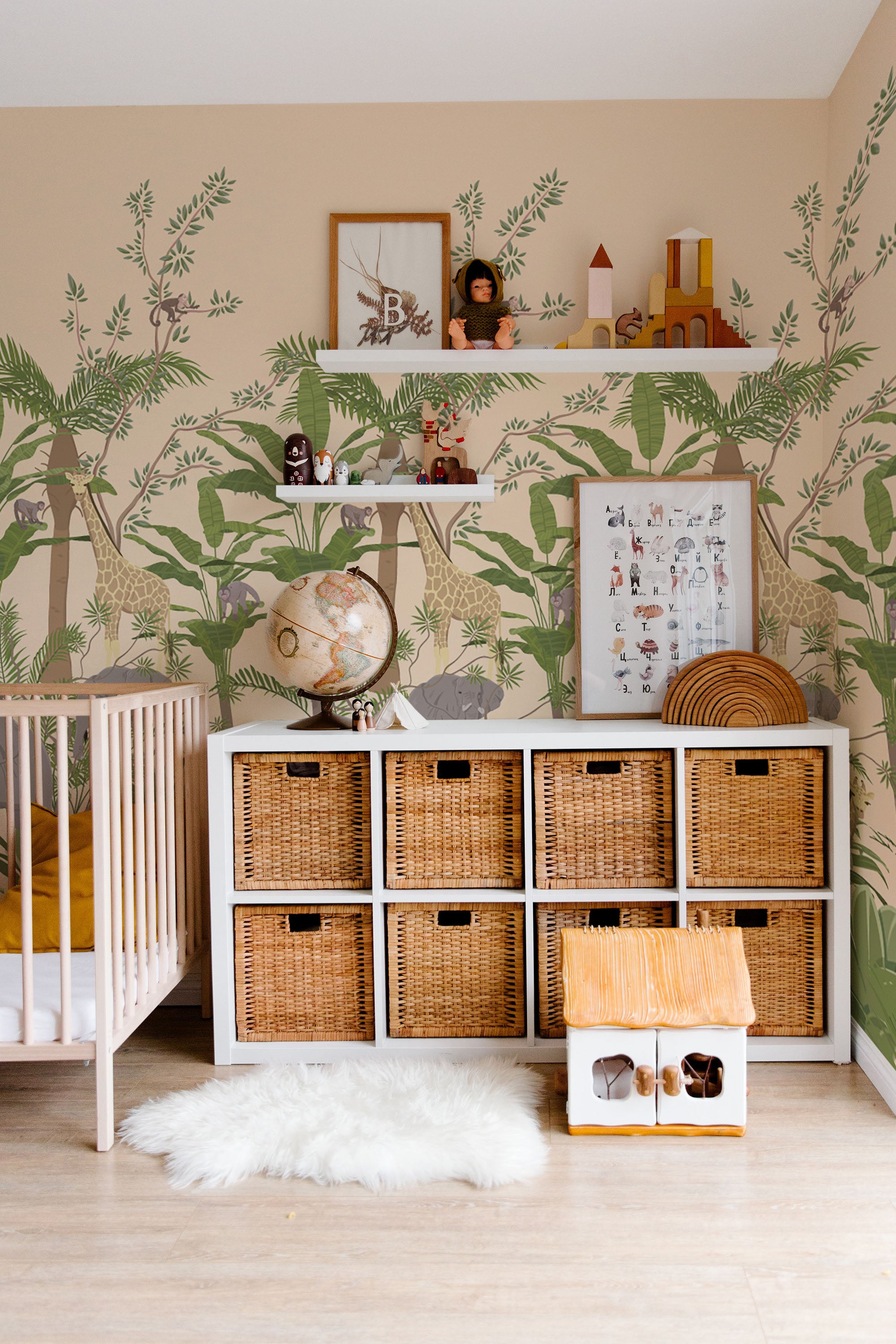 A nursery room with jungle animal-themed wallpaper including trees, leaves and subtle outlines of giraffes, depicting a serene wildlife scene on a traditional wallpaper.