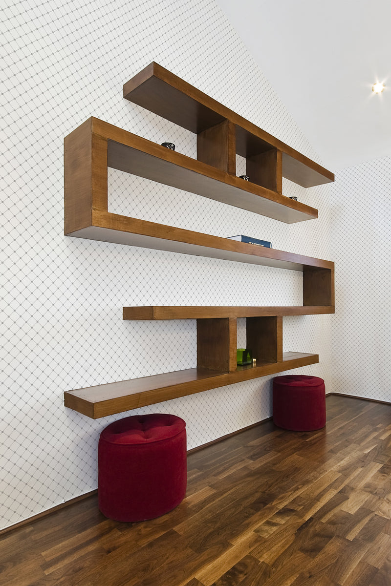 A room with white wallpaper that has a delicate, repeating diamond pattern in light grey lines, giving the wall a subtle, elegant texture. The wallpaper complements the modern wooden floating shelves and rich wood flooring, creating a harmonious blend of contemporary and traditional elements. Traditional wallpaper.