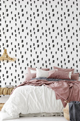 Wallpaper with irregular black brushstroke and rectangular patterns on a white background, creating a minimalistic, hand-painted design in a modern bedroom setting. Traditional wallpaper.