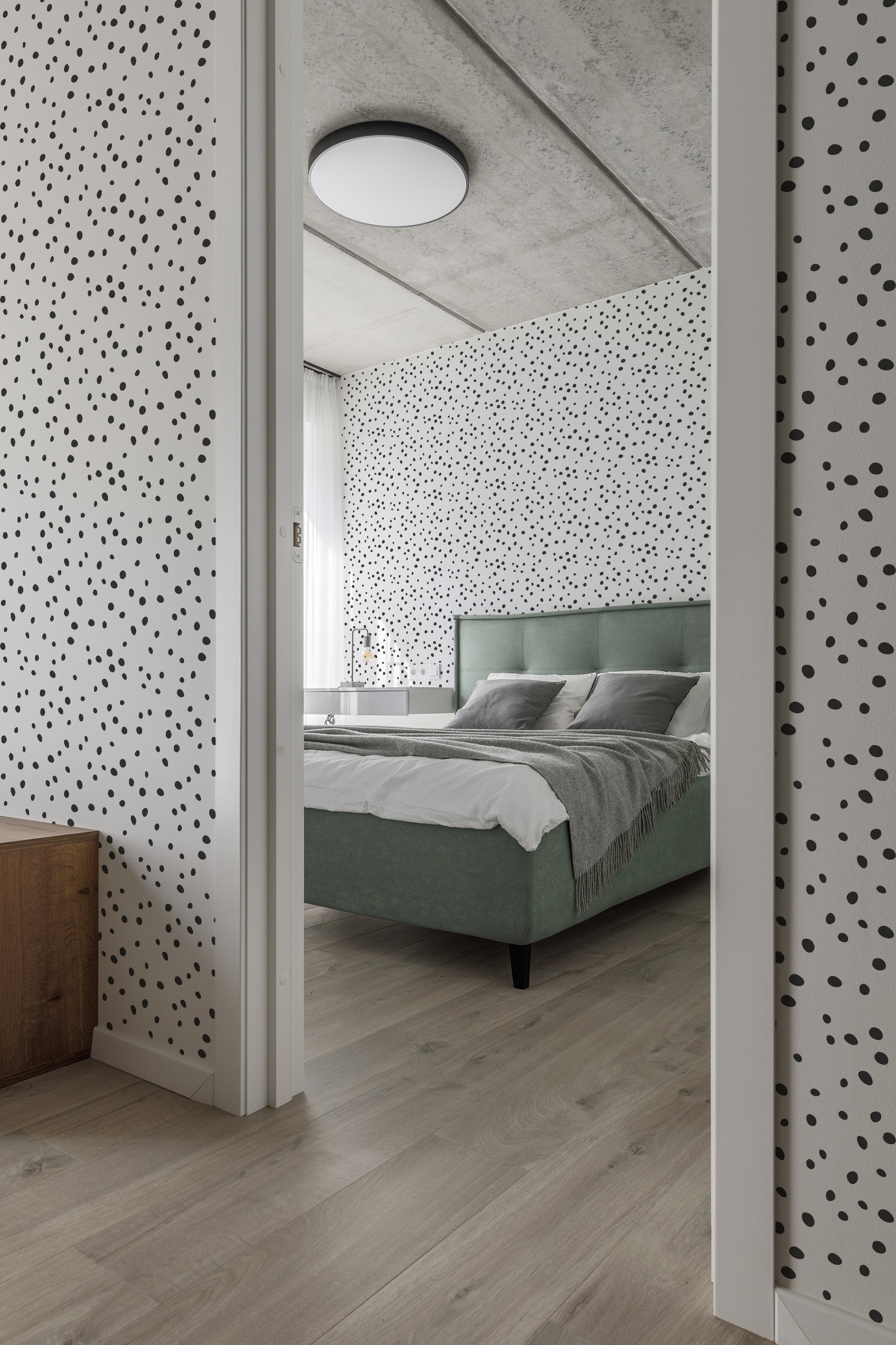 Room with white wallpaper covered in irregular black polka dots, offering a speckled pattern effect that contrasts with the minimalist decor, creating a playful yet classic aesthetic in traditional wallpaper.