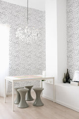 Room with a wall adorned in a white background with small, evenly spaced black dots creating a simple yet elegant pattern,raditional wallpaper.